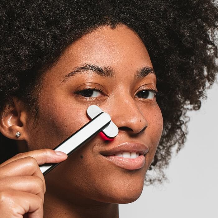 An image of a woman using the Solawave red light therapy wand at home