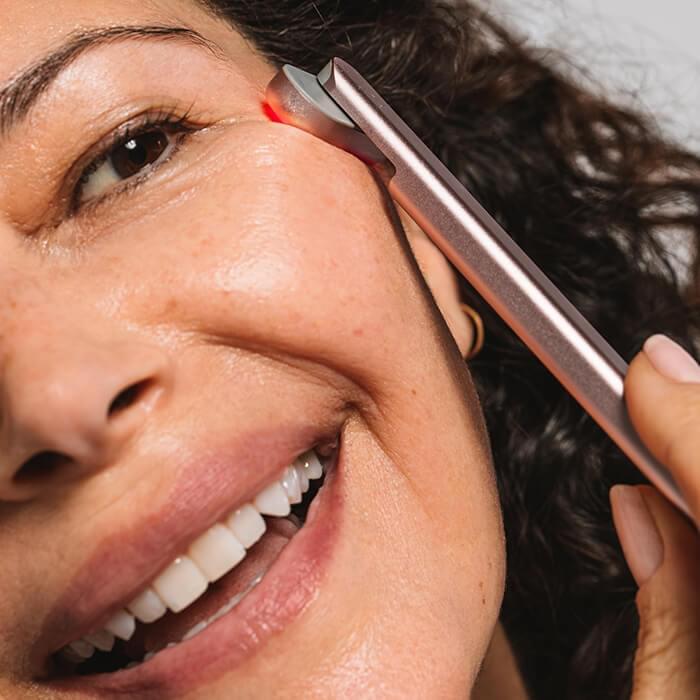 An image of a woman using the Solawave red light therapy wand on her face