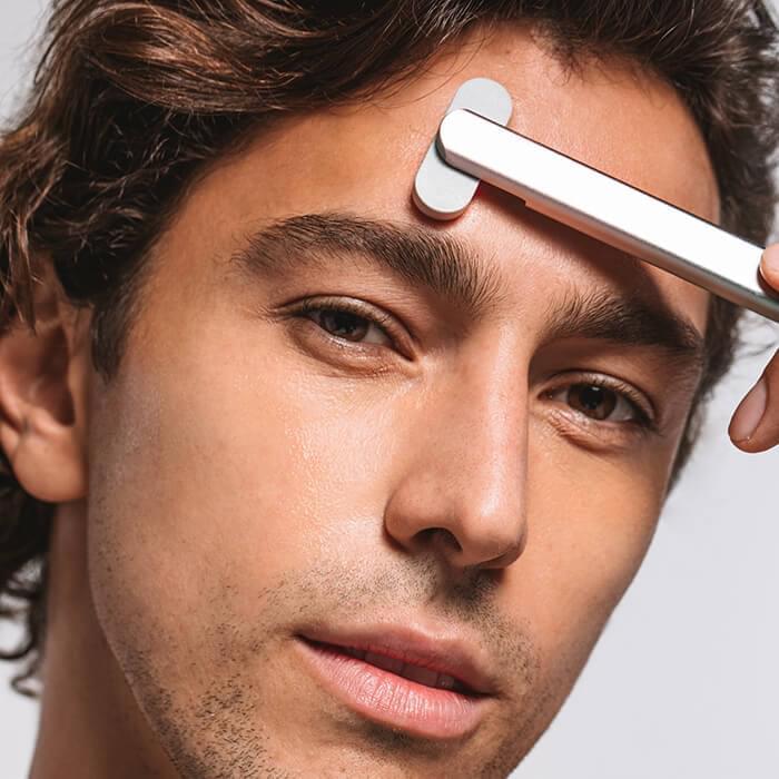 An image of a man using the Solawave red light therapy wand on his forehead