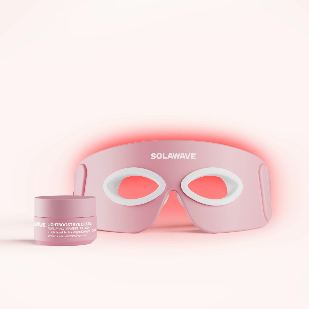 The Eye Recovery Pro Kit includes a rose LED face mask with SolaWave branding and an anti-aging eye mask design, along with a jar of LightBoost Eye Cream. Featuring LightBoost technology, the mask has eye cutouts and white details against a soft pink gradient.