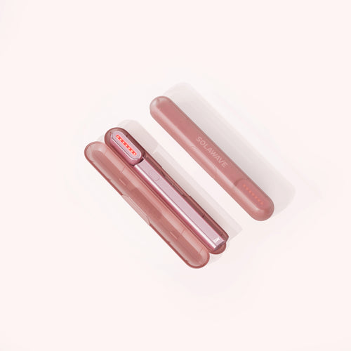 Two pink cylindrical devices, including the Solawave Radiant Renewal Skincare Wand Replacement Carrying Case, are arranged diagonally on a light background. One stands vertically while the other rests horizontally, featuring a sleek design with curved edges and small holes on one end. || Rose Gold